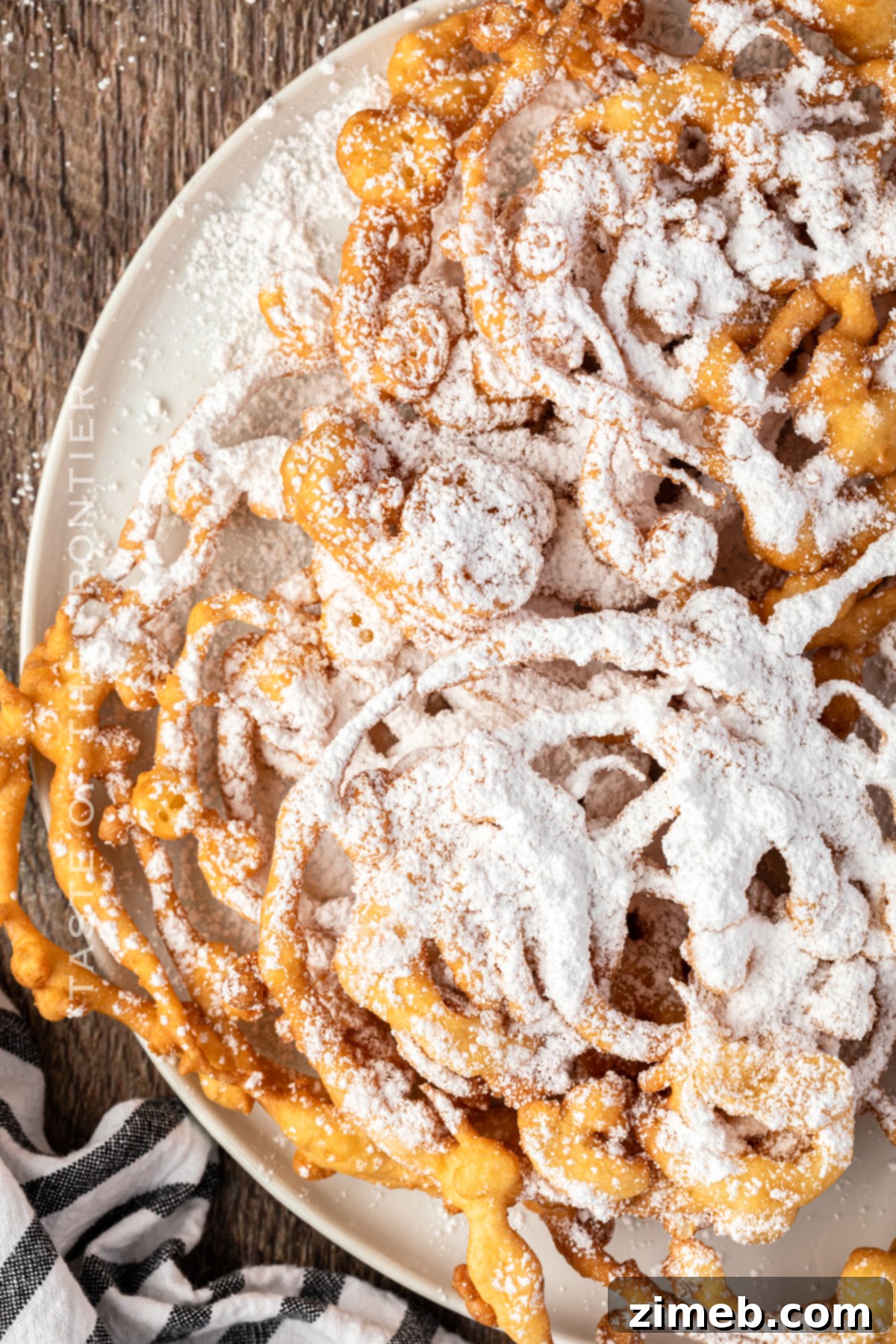 A stack of golden Funnel Cakes on a cooling rack, the best recipe for fair food.