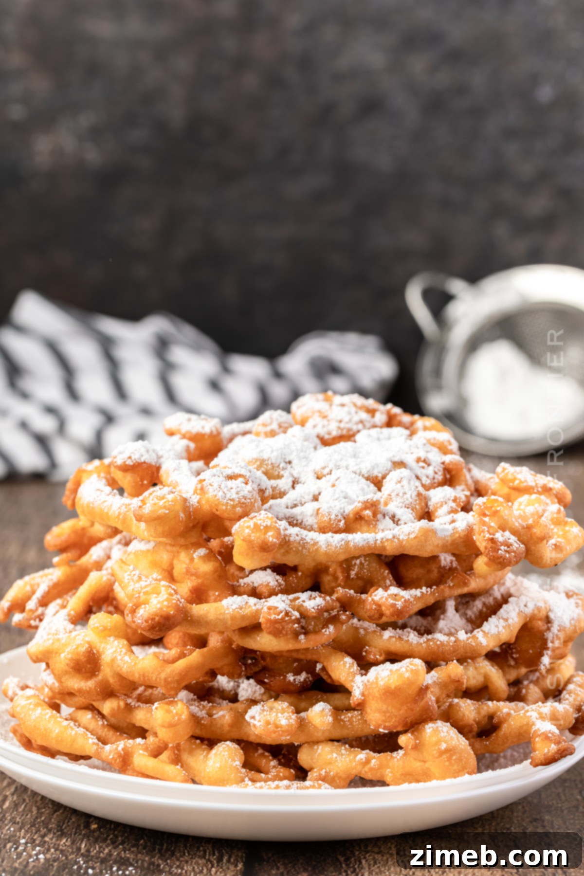 An appetizing stack of homemade Funnel Cake, dusted with powdered sugar, ready to be served.