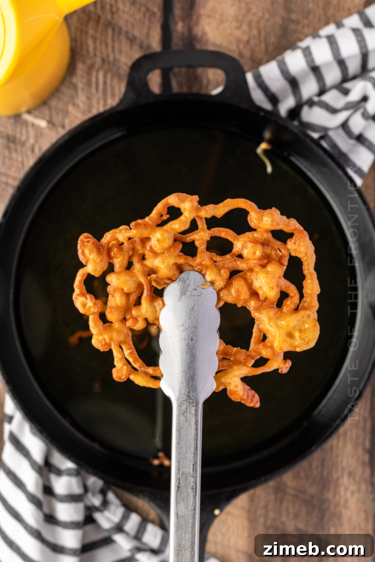 Golden-brown Funnel Cake frying in hot oil, showcasing the texture.