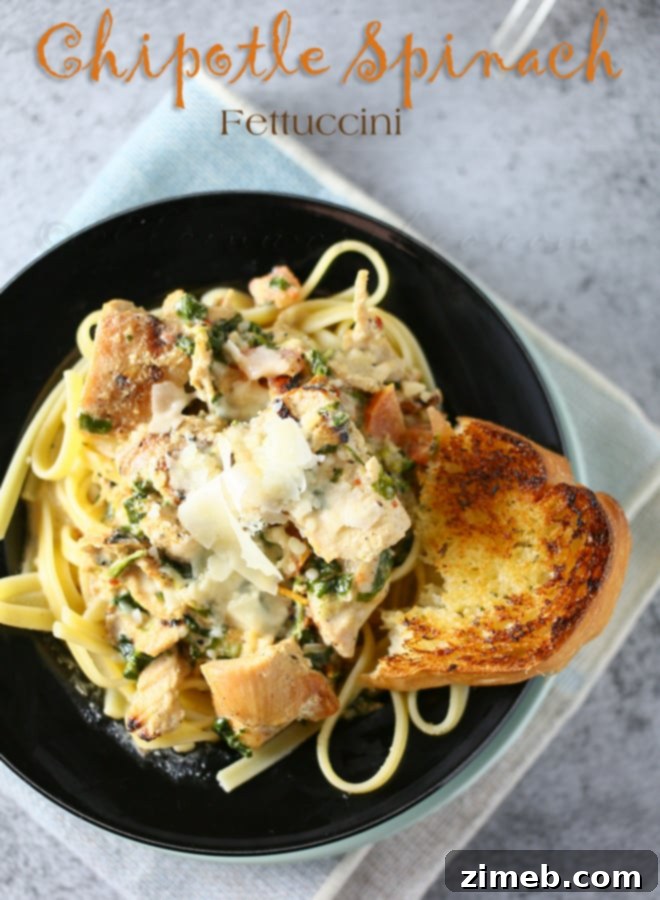 Chipotle Spinach Fettuccini pasta dish in a white bowl, garnished with fresh herbs.