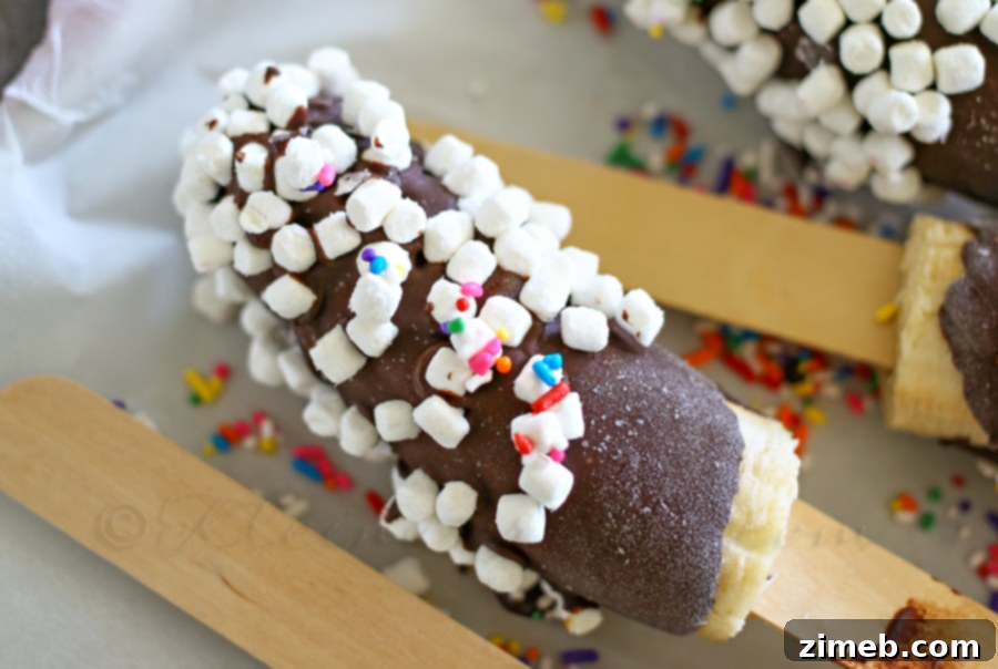 A large batch of chocolate-covered frozen bananas on a tray, ready to be stored or served.