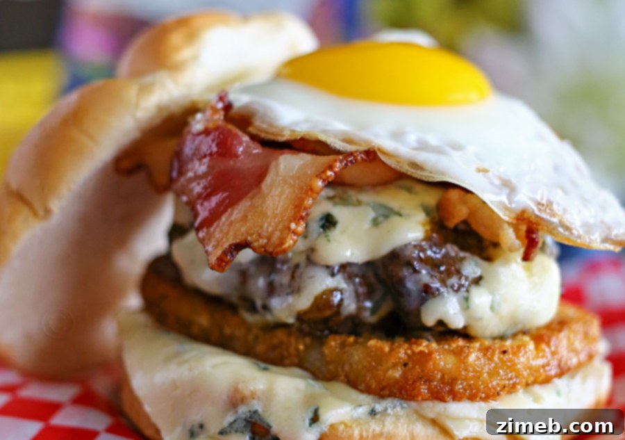 Blue Cheese Sunrise Stack 4 A beautifully assembled Breakfast Burger with all its components visible: bun, hash brown, ground chuck patty, bacon, and a sunny-side-up egg.
