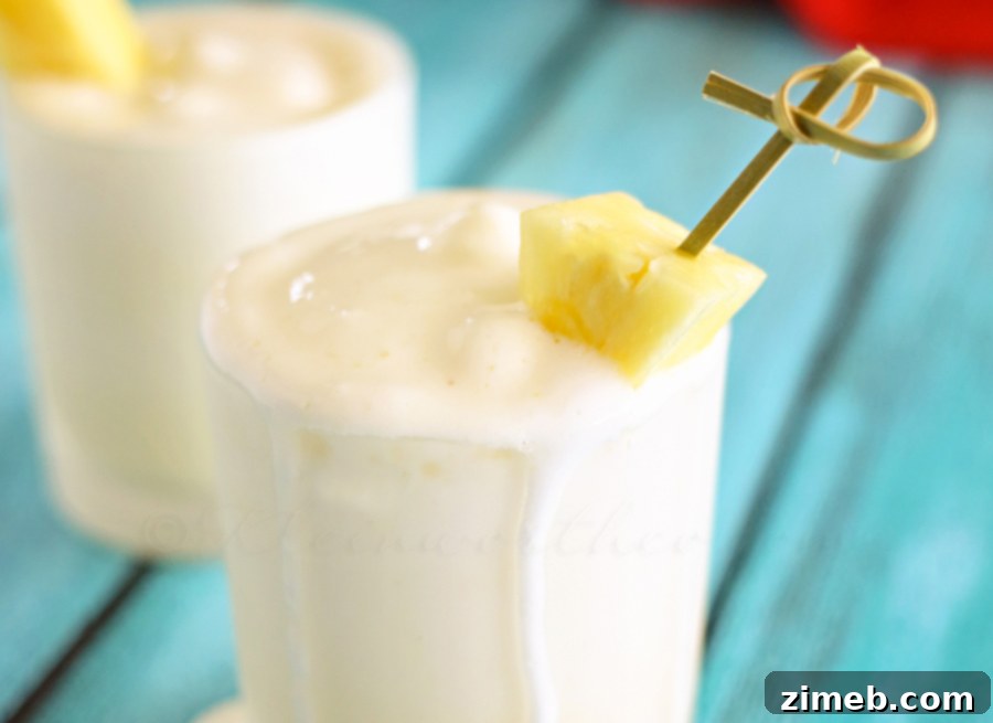 Tropical Pineapple Chill 2 Refreshing Pineapple Cooler in a glass, garnished with a pineapple slice.