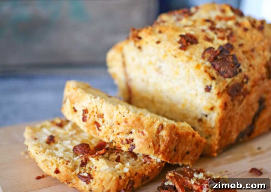 Close-up of a warm slice of Bacon Cheddar Beer Bread, showcasing the fluffy texture, melted cheddar, and visible bacon bits within.