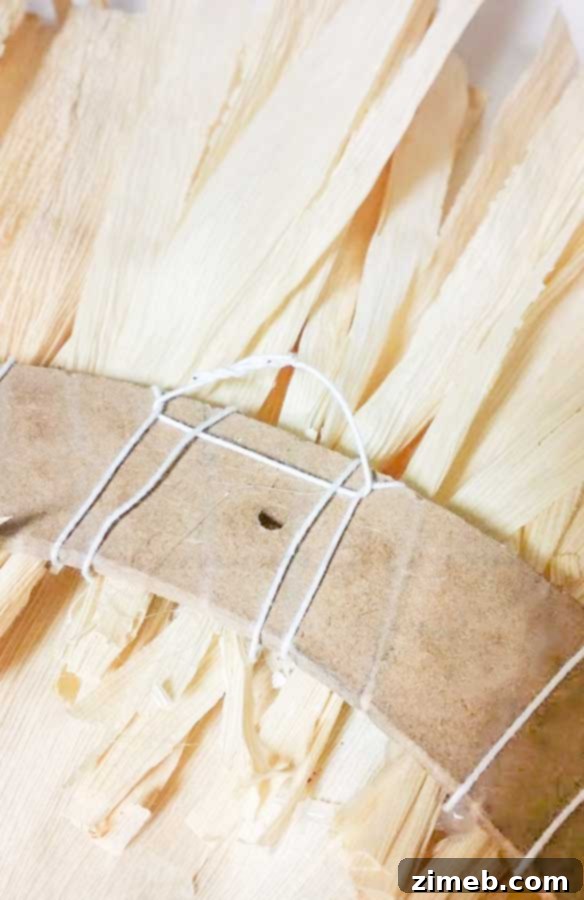 A loop of floral wire being attached to the back of the corn husk wreath for hanging