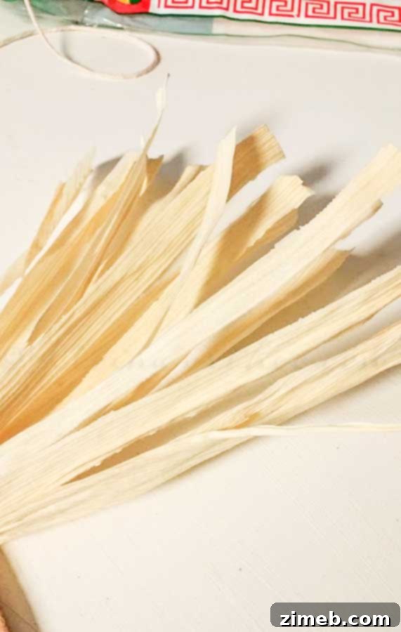 Hands tearing the ends of corn husks to create a frayed, rustic texture for a wreath
