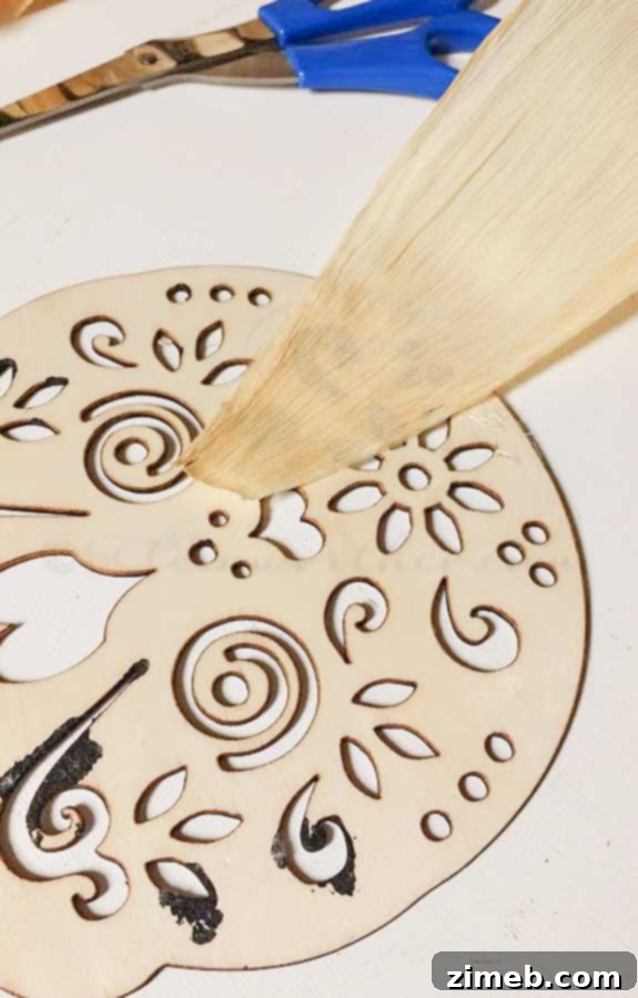 Hot glue being used to attach additional corn husks to the back of the decorated sugar skull cutout