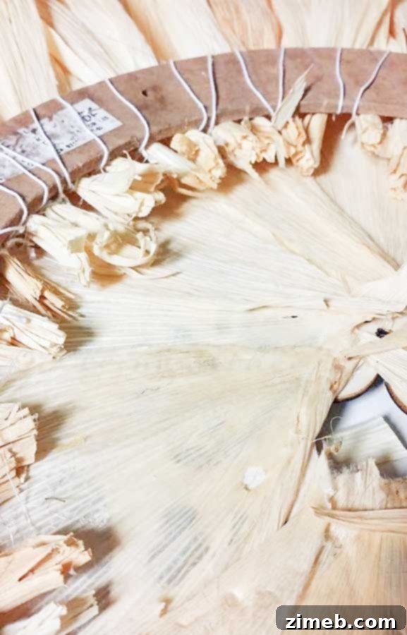 A decorated sugar skull being hot glued to the center of a corn husk wreath