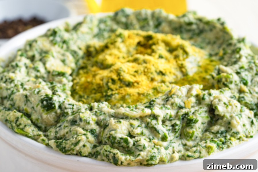 Irresistible Vegan Spinach Artichoke Dip 3 Dairy-free Spinach Artichoke Dip in a white baking dish, ready to be served, highlighting its smooth and rich texture.