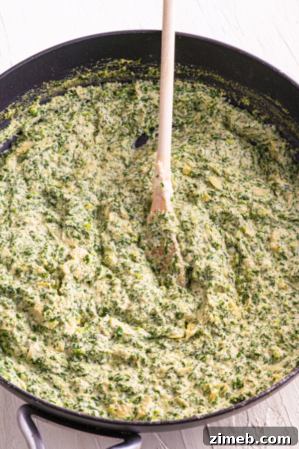 Irresistible Vegan Spinach Artichoke Dip 8 The best Vegan Spinach Artichoke Dip served hot in a small white bowl with pita bread and vegetable sticks.
