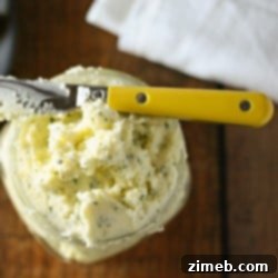 Skillet-Baked No-Knead Parmesan Loaf 11 Overhead view of whipped butter with garlic and chives in a jar with a butter knife laying on top.