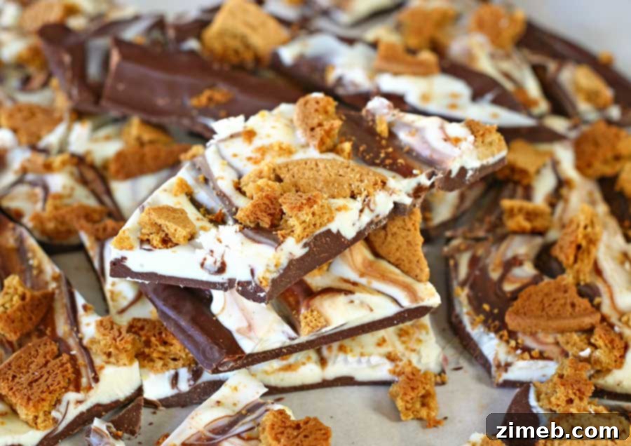 Gingerbread Snap Bark 4 Sliced Gingerbread Cookie Bark on a platter, showcasing the distinct layers of milk chocolate, white chocolate, and gingerbread cookie crumbles.