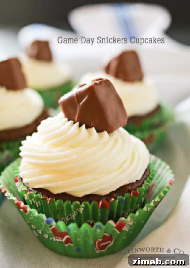 Score Big Snickers Cupcakes 6 A tray of freshly frosted Game Day Snickers Cupcakes, adorned with Snickers minis, ready for a football party.