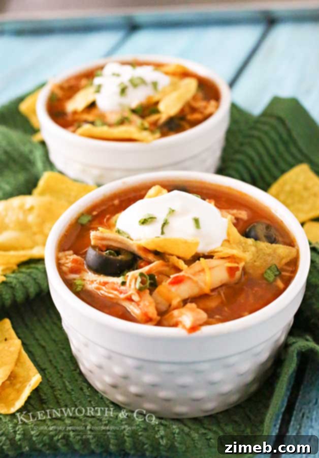 Set-It-and-Forget-It Chicken Tortilla Soup 4 Slow Cooker Chicken Tortilla Soup served in a rustic bowl, garnished with avocado slices, a dollop of sour cream, and crispy tortilla strips, ready for a cozy meal.