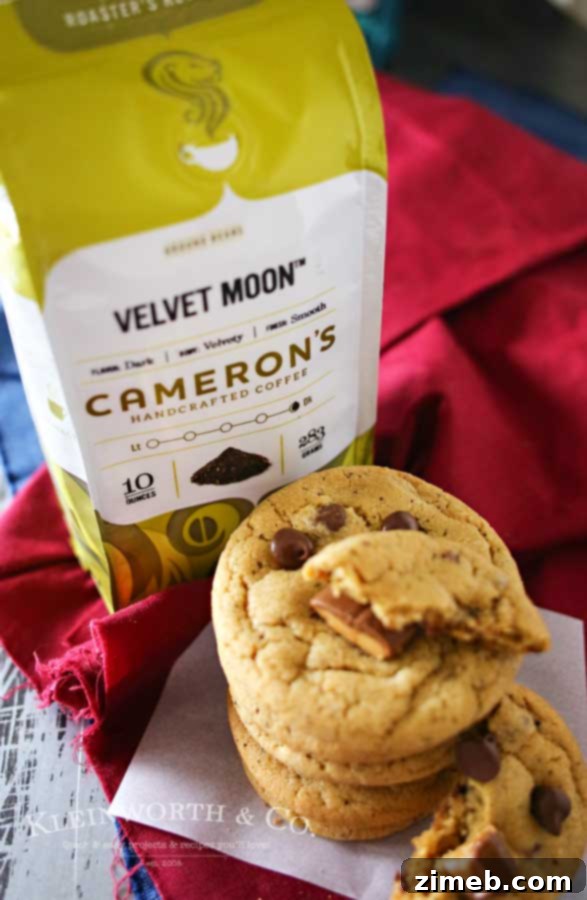 A delectable close-up of a Coffee Toffee Cookie, showcasing its soft, inviting interior, studded with generous amounts of melted chocolate chips and crunchy toffee pieces.