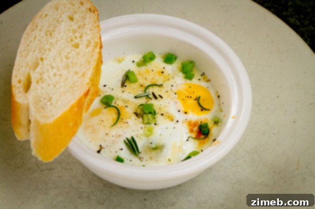 25 Delicious Egg Recipes 10 Baked Asiago & Rosemary Eggs, a gourmet individual egg dish.