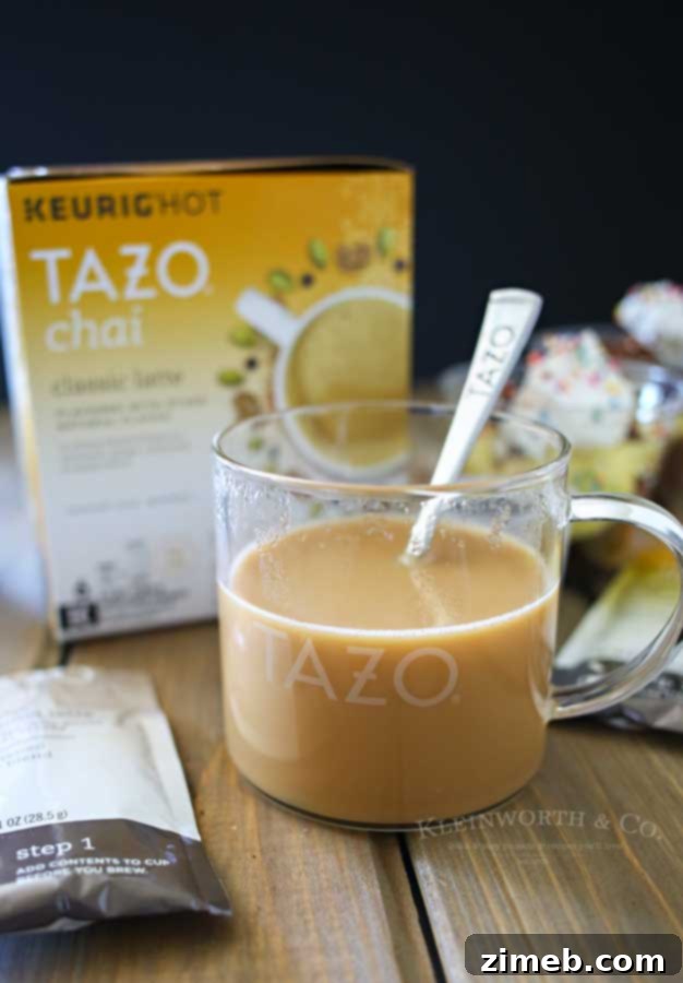 Chai and Mini Crash Cake Delights 3 Two hands gently holding a mini crash cake and a warm mug of TAZO Chai Tea, set against the blurred, inviting backdrop of an evening porch scene, emphasizing comfort and relaxation.
