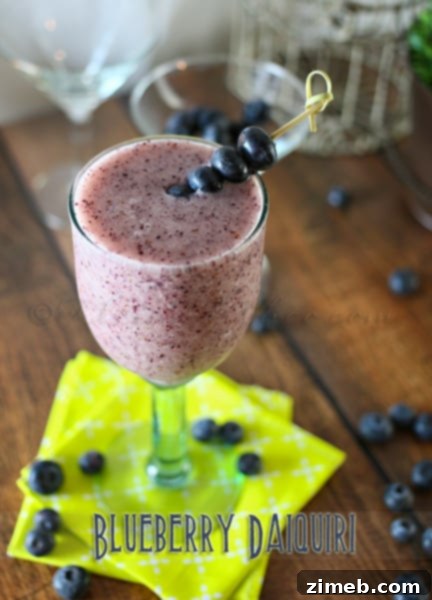 Peachwood Palmer 8 Vibrant Blueberry Daiquiri in a stemmed glass with fresh blueberries and lime.