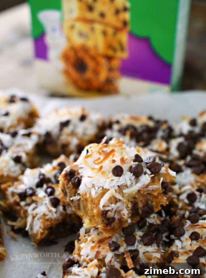 Cross-section of a Caramel Coconut Blondie slice, showing layers of the buttery blondie base, thick caramel, toasted coconut, and melted chocolate.
