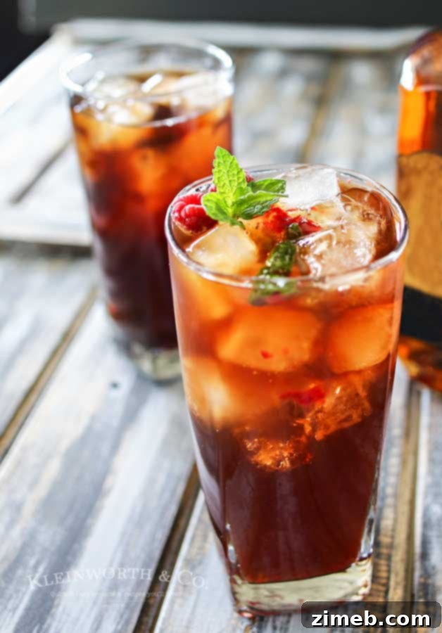 Spirited Raspberry Mint Iced Tea 3 A close-up of Raspberry Mint Hard Iced Tea, showing the vibrant raspberries and green mint leaves in a glass, with a refreshing appeal.