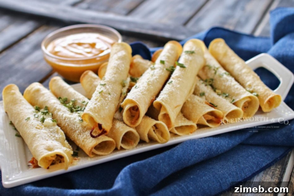 Crispy Pulled Pork Roll-Ups 3 Close-up of golden brown Baked Pulled Pork Taquitos on a serving platter with dipping sauce