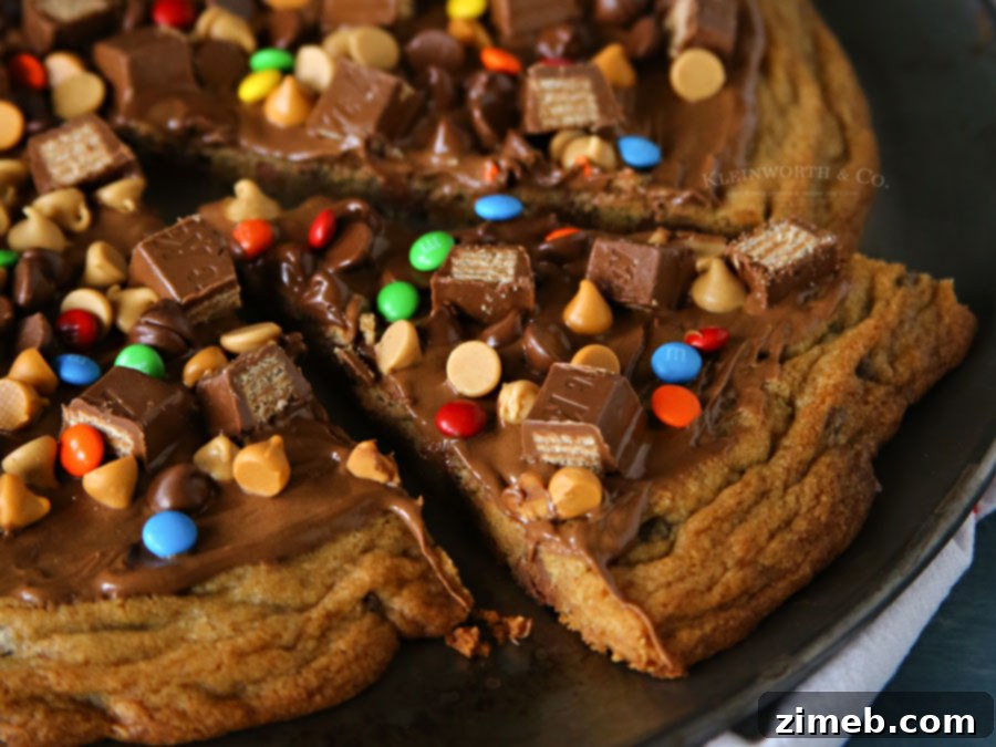 Ultimate Chocolate Chip Cookie Pizza 3 A whole Loaded Chocolate Chip Cookie Pizza fresh out of the oven, showcasing its golden-brown cookie base and a vibrant, overflowing topping of various candies and melted chips.