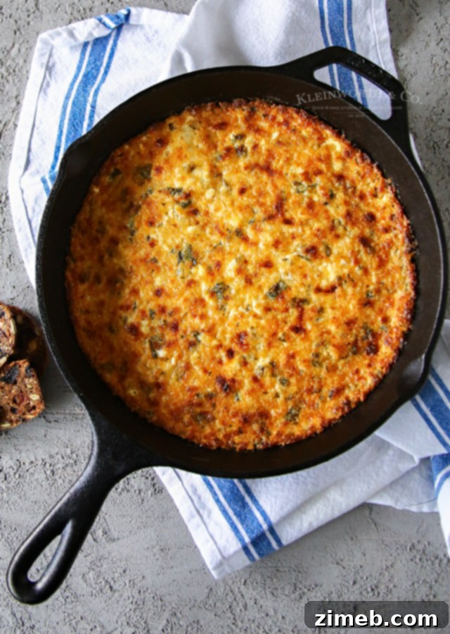 Velvety Hot Havarti Spinach Dip 4 A close-up of Cheesy Havarti Hot Spinach Dip in a cast iron skillet with a scoop taken out, ready to be served.