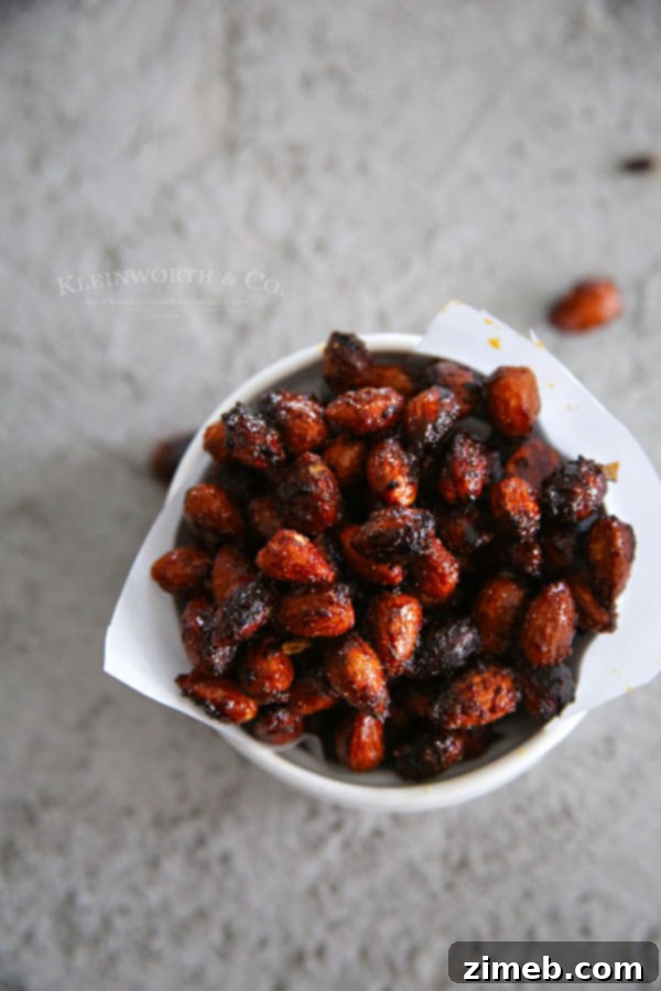 Hand reaching for a Sriracha Spice Almond from a bowl, emphasizing their irresistible nature.