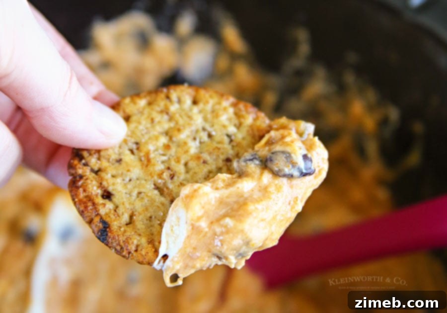 Spread of Slow Cooker Fiesta Cheese Dip with crackers and other snacks, perfect for a party.