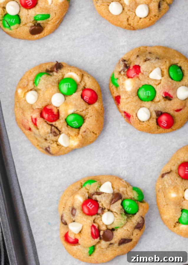 A perfectly baked chocolate chip cookie adorned with red and green M&Ms, glistening with melted chocolate.