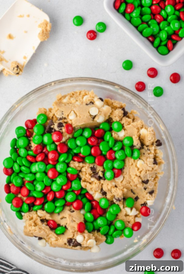 Mixing colorful M&Ms into a bowl of rich chocolate chip cookie dough.