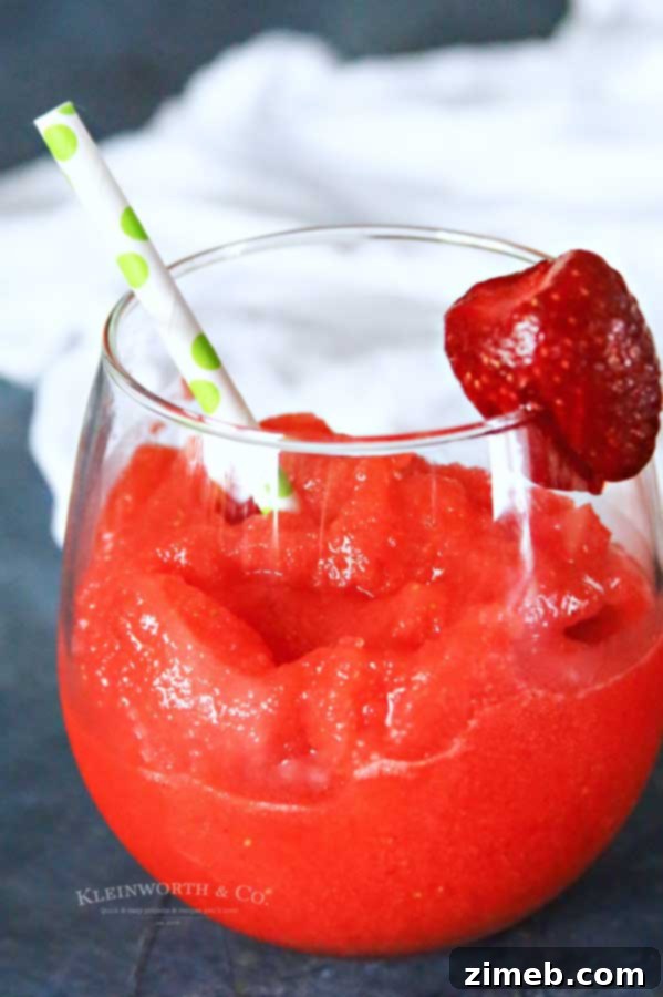A pitcher of homemade Strawberry Daiquiri next to a garnished glass.