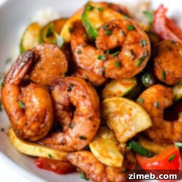 Grilled shrimp on a white plate with grilled squash and peppers.