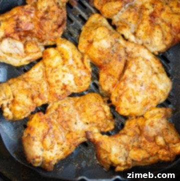 Close-up of air-fried chicken thighs in an air fryer basket.