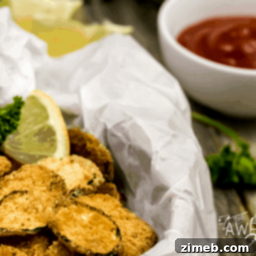 Close-up of crispy zucchini chips, thinly sliced and baked to a golden-brown perfection, piled in a parchment lined basket, showcasing their light, crunchy texture and seasoned edges
