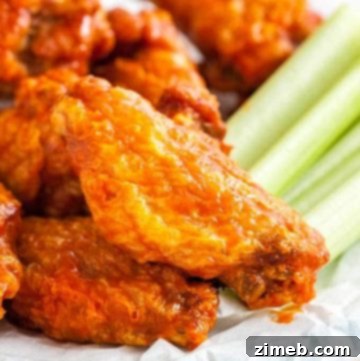 Close-up of crispy air-fried chicken wings arranged on a plate, garnished with fresh celery sticks, showing a golden-brown exterior.