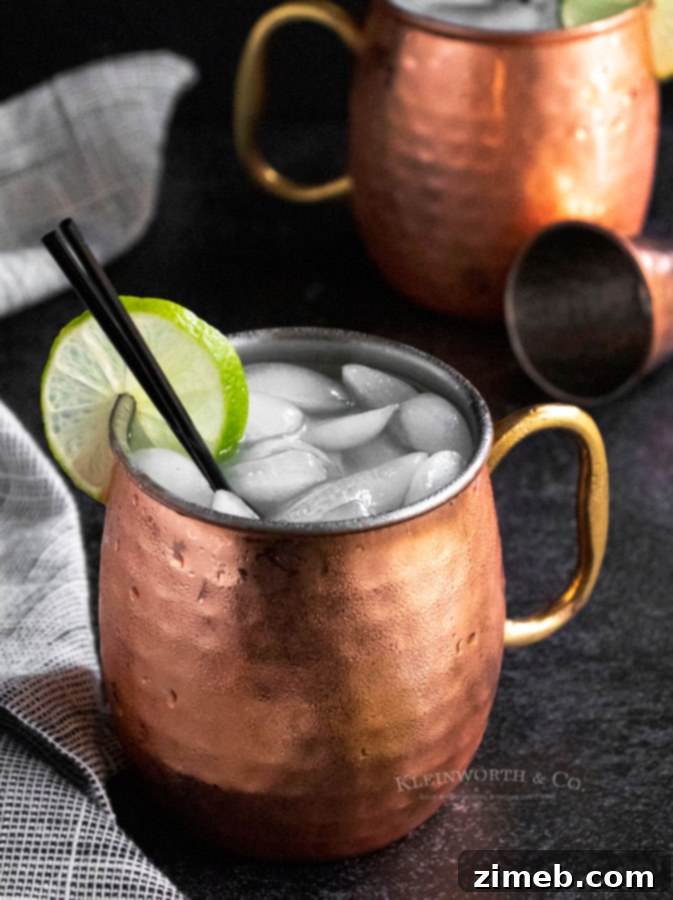 Cinnamon Ember Mule 5 Christmas Mule cocktail, garnished with lime and cinnamon sticks, perfect for holiday entertaining.