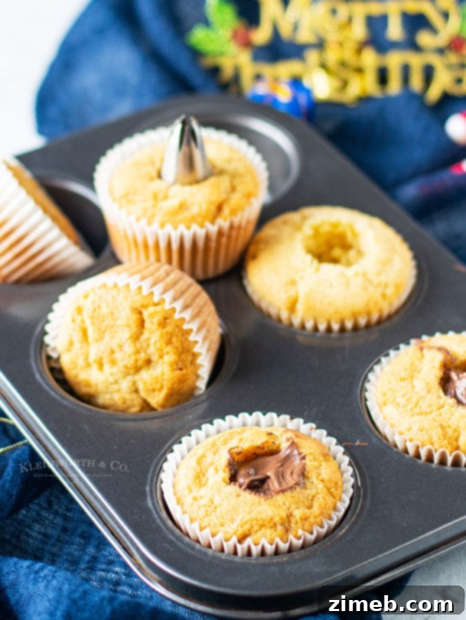 Close-up of a vanilla cupcake being filled with rich Nutella hazelnut spread.