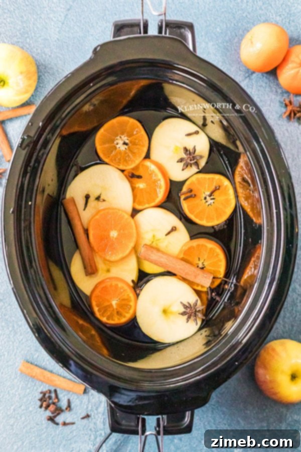 Golden Bourbon Apple Brew 7 A close-up shot of crockpot spiked apple cider, showing the spices and fruit floating.