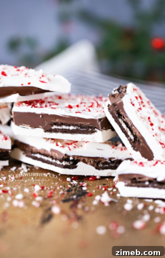 Hands breaking apart a sheet of homemade Oreo Peppermint Bark