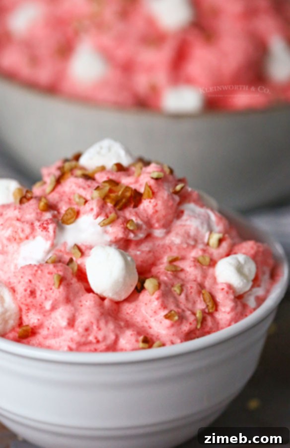 A bowl of ready-to-serve Strawberry Jello Salad recipe, garnished with fresh fruit.