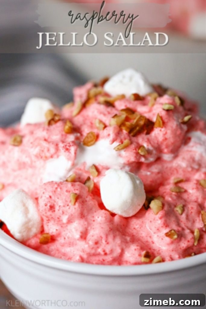 A glass bowl filled with Raspberry Jello Salad Recipe, garnished with fresh raspberries.