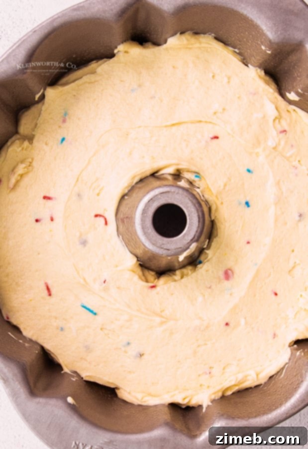 Unbaked 4th of July Bundt Cake batter in a bundt pan, showing vibrant red, white, and blue sprinkles throughout.