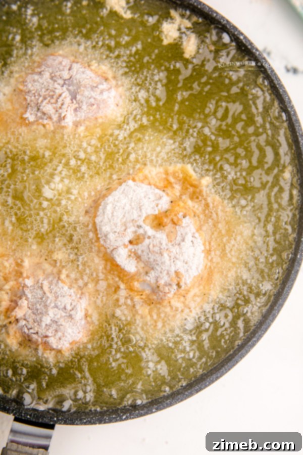 Chicken frying in hot oil in a deep pan