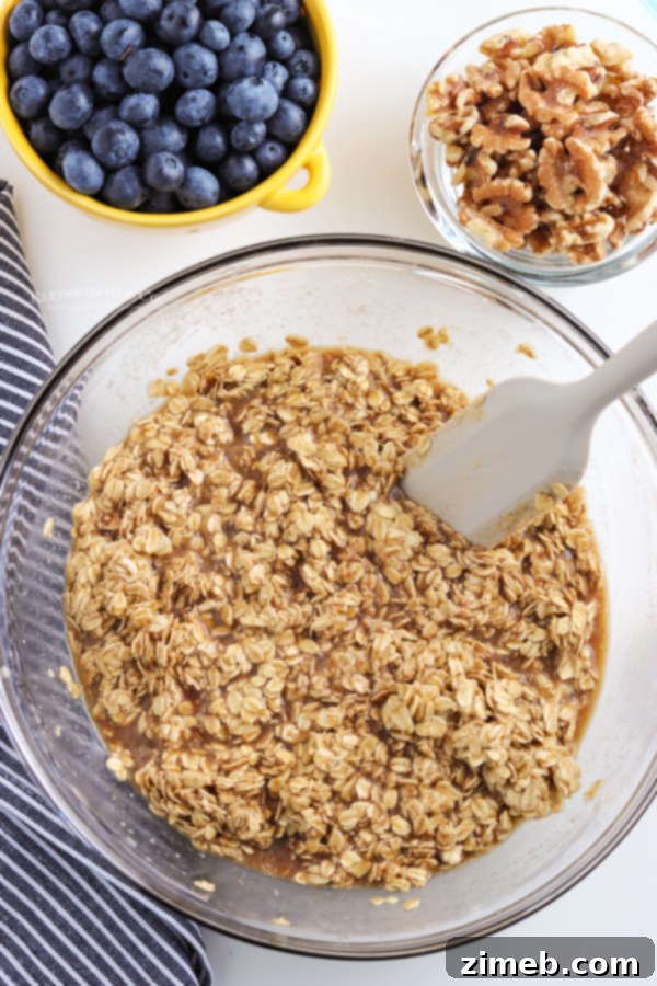 Warm Blueberry Oat Bake 6 Hands mixing the wet and dry ingredients for baked oatmeal in a large white bowl, showing the creamy texture before adding fruit.