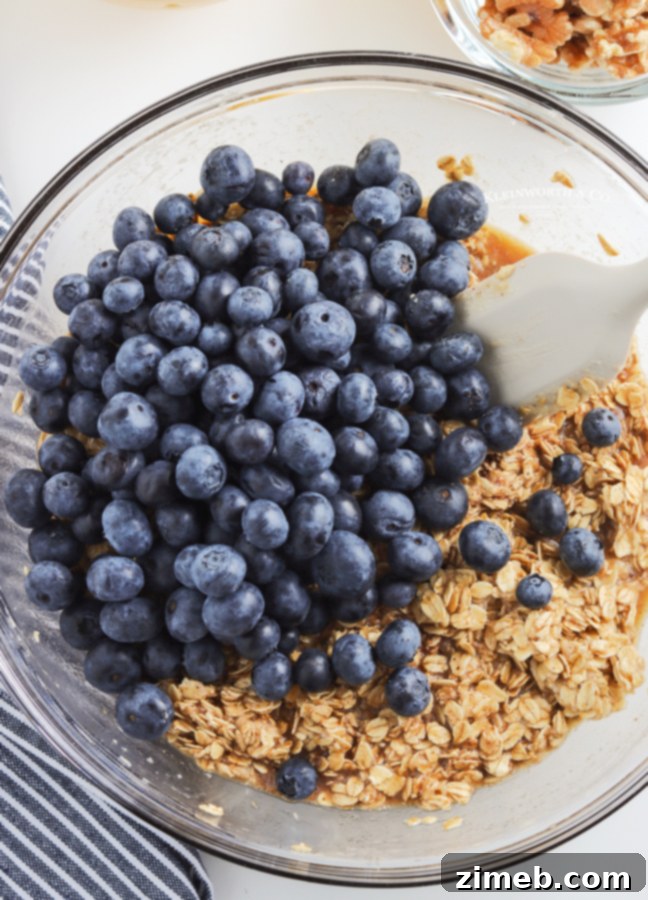Warm Blueberry Oat Bake 7 A rectangular baking dish with an even layer of oatmeal mixture and scattered blueberries, demonstrating the stage before baking, ready to be transformed into a hearty casserole.