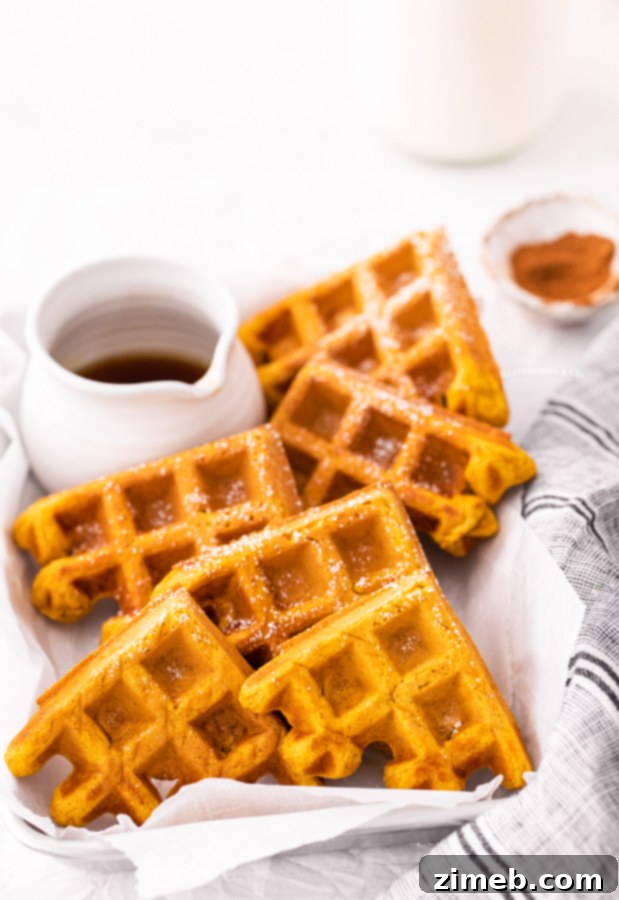 Close up of a stack of pumpkin waffles with syrup and berries