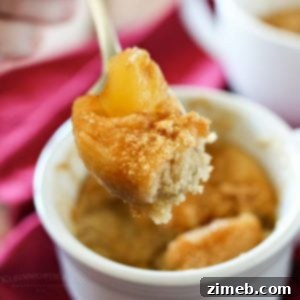 A warm apple pie mug cake in a white mug, topped with bite on a spoon showcasing the rich, comforting dessert in a cozy setting.
