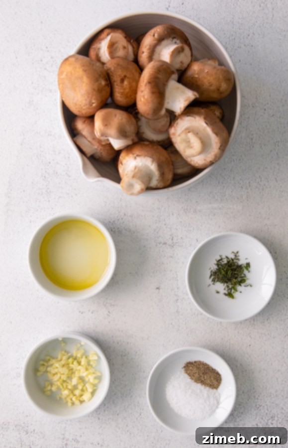 Golden Garlic Thyme Roasted Mushrooms 5 A sheet pan filled with ingredients for oven roasted mushrooms: cremini mushrooms, olive oil, minced garlic, fresh thyme, salt, and pepper.