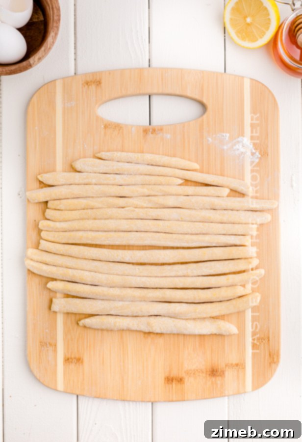 Hands demonstrating the shaping of Struffoli dough into ropes